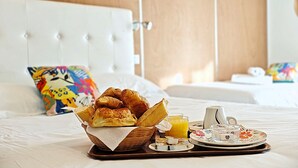 A breakfast tray with croissants, orange juice, and a small dish of cheese on a bed in a hotel room. - Hotel Le Florian (Cannes)
