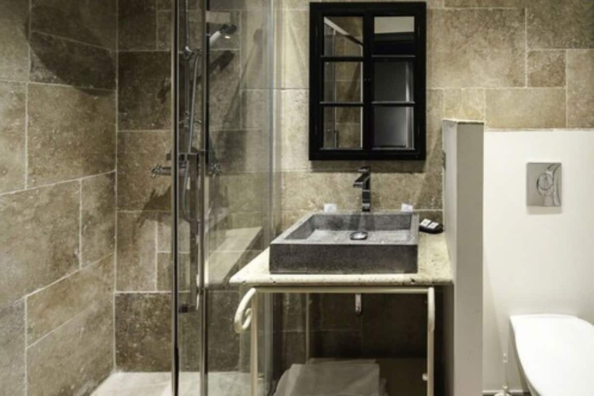 A bathroom with a glass shower enclosure, a sink with a black countertop, and a white toilet.