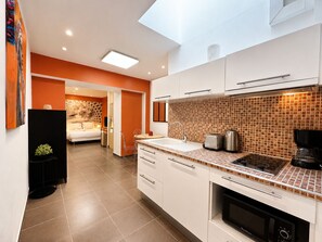 A modern kitchen with white cabinets, a tiled backsplash, and a built-in oven. - Hotel Le Florian (Cannes)