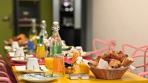 A breakfast table with plates, glasses, and a basket of pastries. - Hotel Le Florian (Cannes)