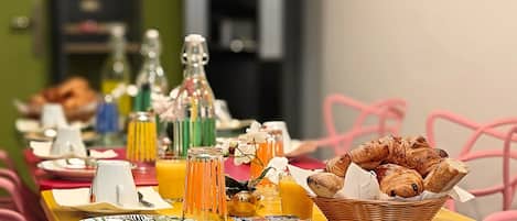 A breakfast table with plates, glasses, and a basket of pastries.
