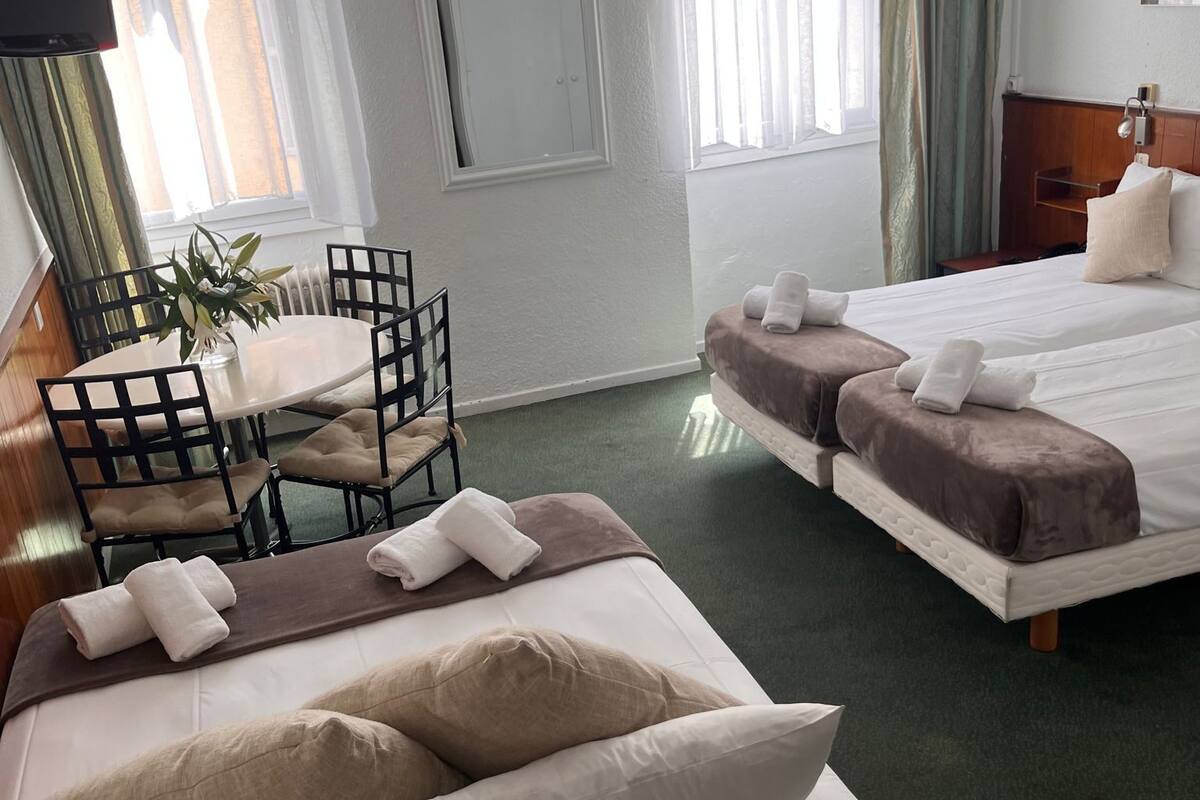 Una habitación de hotel con cama, sofá, una mesita y una silla.