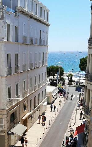 A street with buildings, a clear blue sky, and the sea in the background. - Azurene Royal Hotel (Cannes)