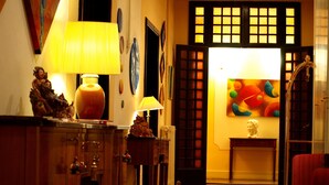 A warmly lit hallway with wooden flooring, a decorative lamp, a statue, and a painting on the wall. - Residenza Johanna I (Florence)