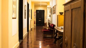 A hallway with wooden flooring, a red armchair, a table with a bowl, and a black door. - Residenza Johanna I (Florence)