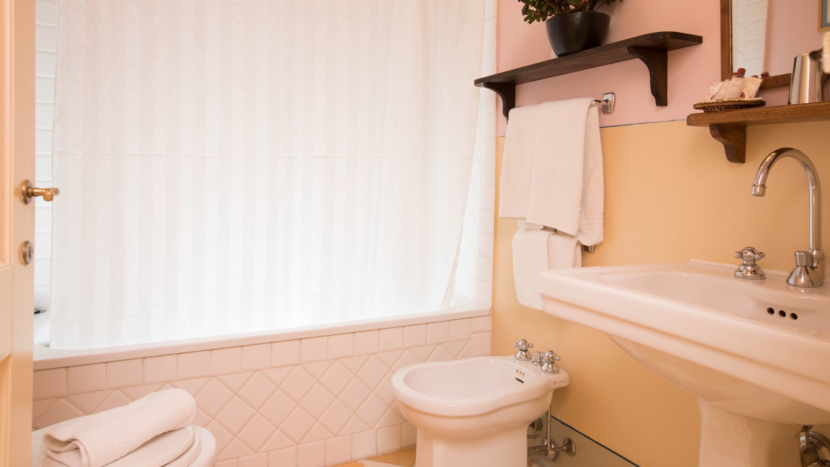 Ein Badezimmer mit Badewanne, Waschbecken und Toilette. Ein Handtuchhalter mit einem daran hängenden Handtuch.