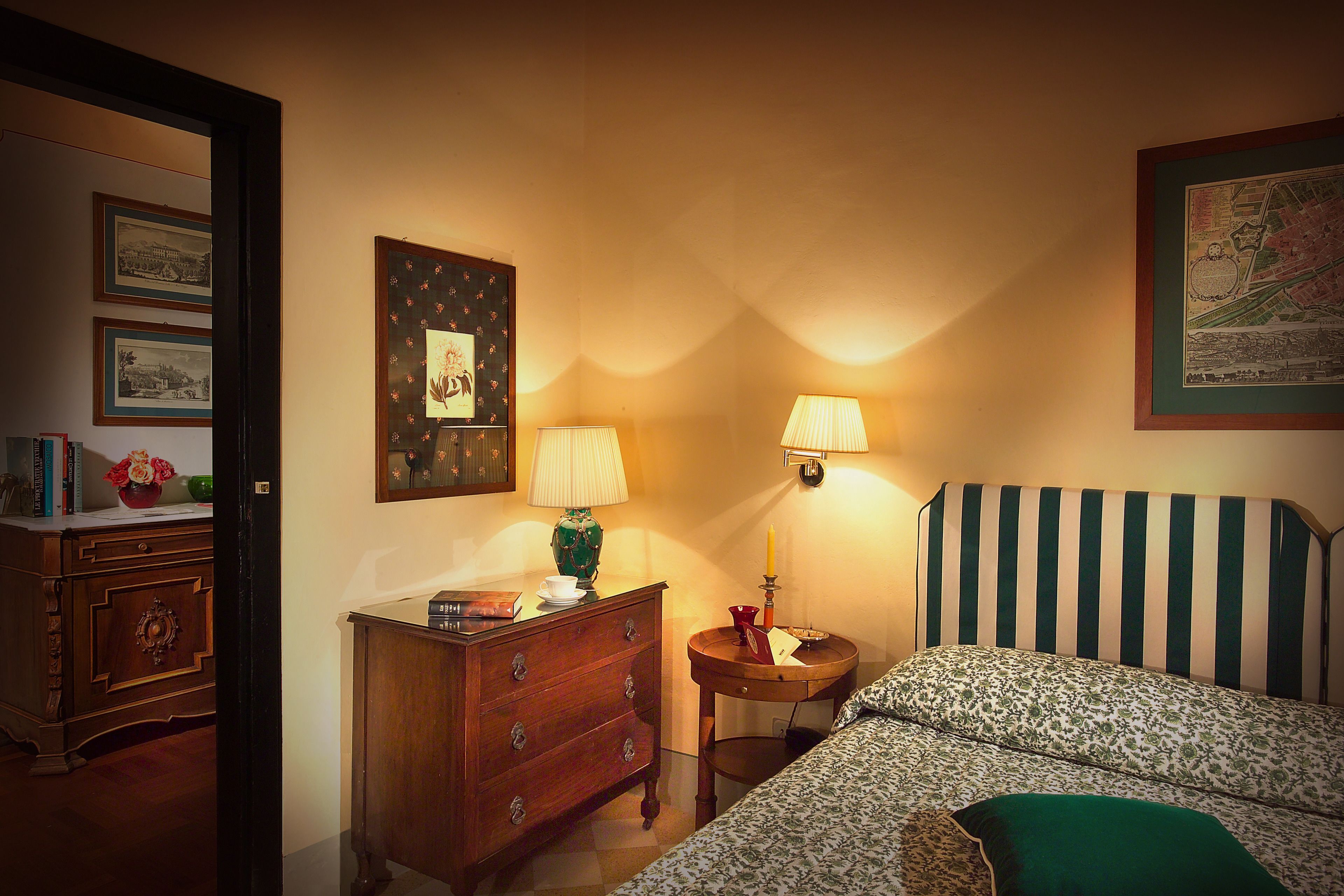 Une chambre à coucher comprenant un lit, une commode, une table de chevet, une lampe et une carte accrochée au mur.