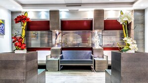A modern reception area with a sofa, two side tables, and decorative plants.