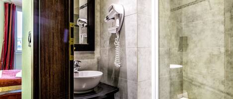 A bathroom with a sink, mirror, towel rack, and a shower area.