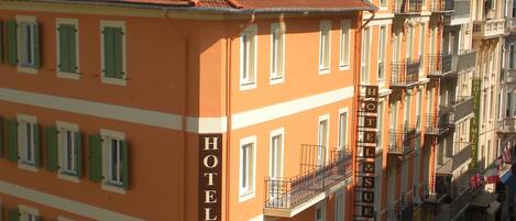 Un hôtel avec une façade rouge, de nombreux balcons et une enseigne indiquant qu’il s’agit d’un hôtel.