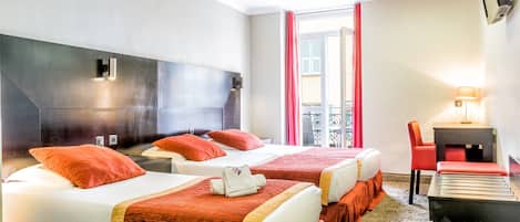 Habitación de hotel con dos camas, un escritorio, una silla y un televisor montado en la pared.
