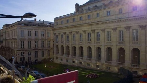 Un grand bâtiment historique à l’architecture classique, doté de nombreuses fenêtres et de portes en arc de cercle.