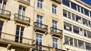 Un hôtel à plusieurs étages doté de balcons, une grande enseigne lumineuse indiquant la présence d’un théâtre, et une voiture garée devant.