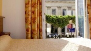 Une chambre d’hôtel avec une grande fenêtre, un lit et des rideaux.