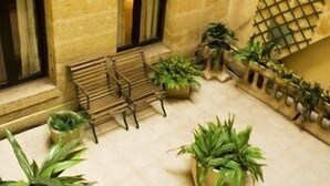 A stone building with a wooden bench, potted plants, and a lattice structure. - Hôtel des 4 Soeurs (Bordeaux)