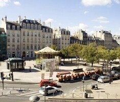 Una vista di strada con edifici storici, un gazebo e auto parcheggiate.