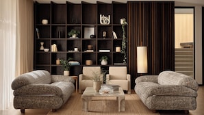 A modern living room with two patterned sofas, a coffee table, and a dark wood bookshelf filled with books and decorative items. - Bob W Munich Schwabing (Munich)