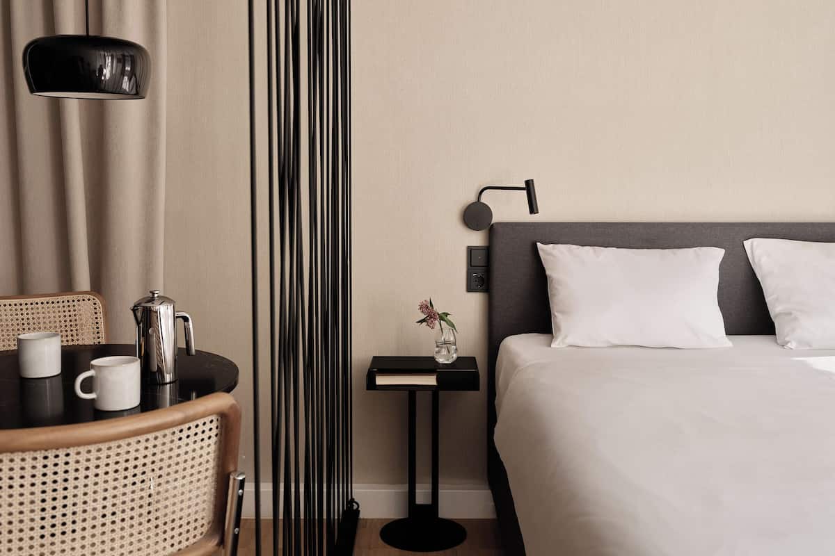 Une chambre d’hôtel avec un lit, une table de chevet, une lampe et une chaise.