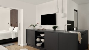 A modern, minimalist bedroom with a large bed, a bedside table, and a nightstand. - Bob W Munich Schwabing (Munich)