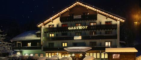 A hotel with a sign reading "GASTHOF" and multiple cars parked in front.