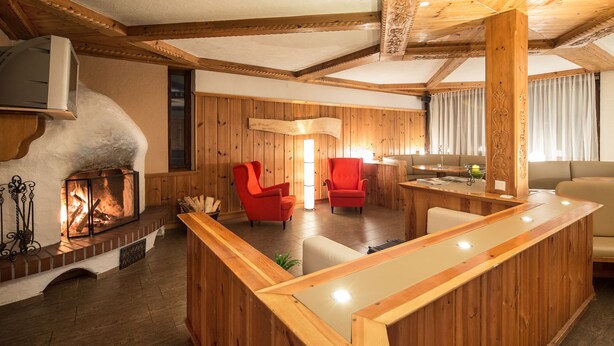 Un interior de madera con chimenea, sillas rojas y un mostrador de recepción de madera.