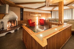 Un interior de madera con chimenea, sillas rojas y un mostrador de recepción de madera.