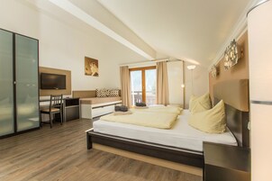 Una habitación de hotel moderna con una cama grande, un escritorio, una silla, un televisor y una puerta corredera.