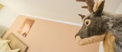 Una decoración de cabeza de venado de aspecto lujoso en una habitación con pared color beige y un cuadro enmarcado.
