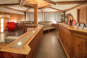Un interior de madera con una recepción, un sillón rojo, un sofá y un comedor.