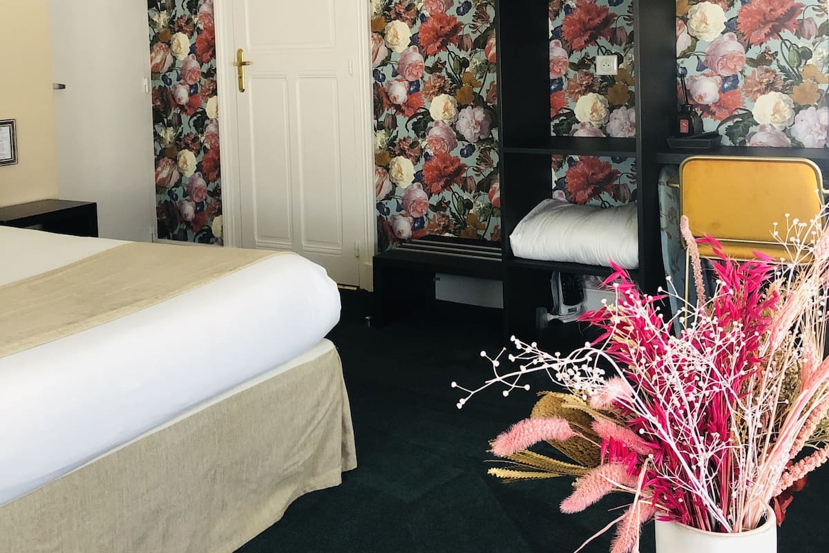 Un dormitorio con una cama, un armario, una silla y un jarrón decorativo.