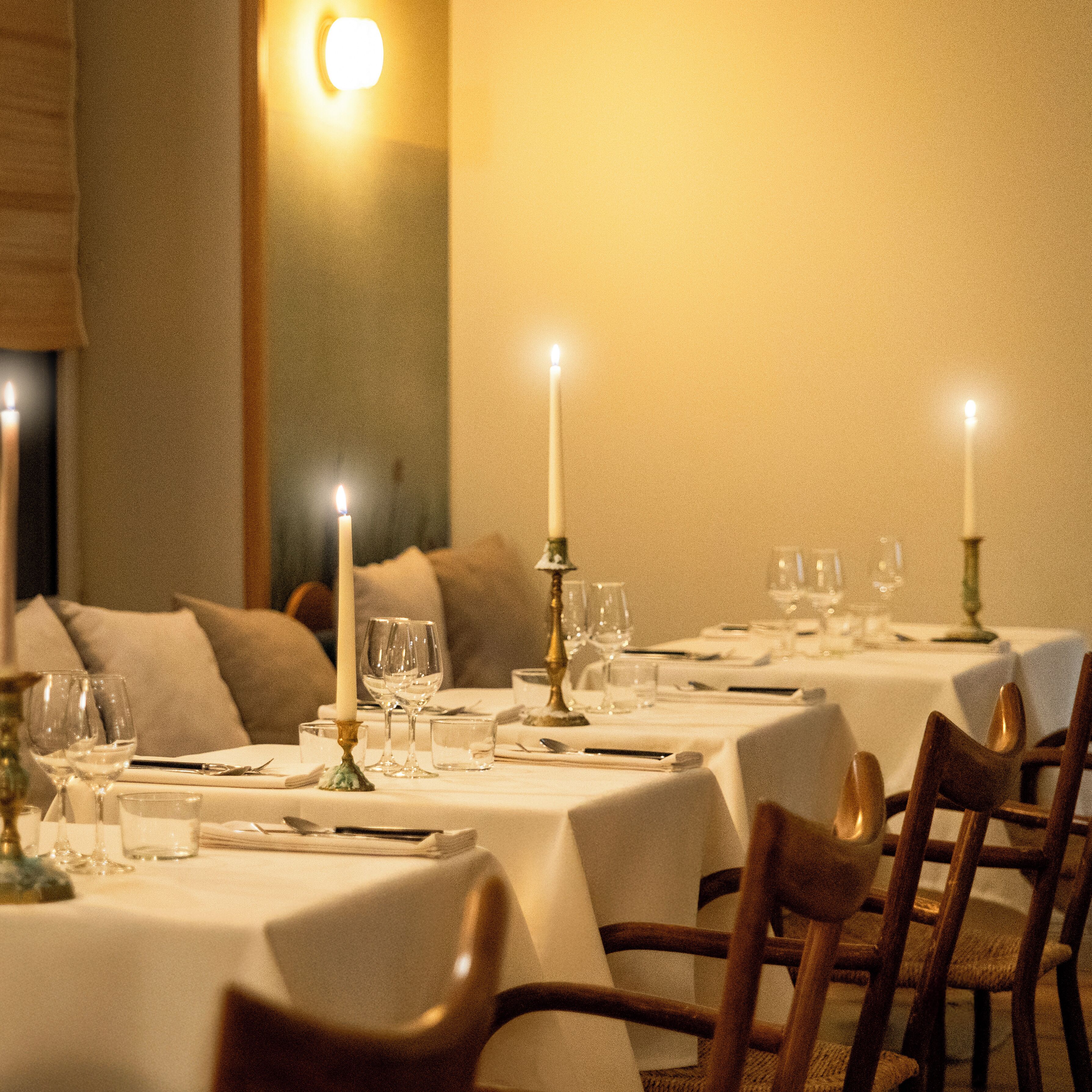 Un espace repas avec des tables mises pour le dîner, des bougies et des verres.