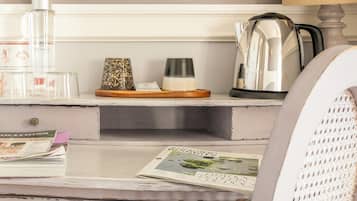 A room with a white dresser, a mirror, a kettle, and a magazine on the counter.