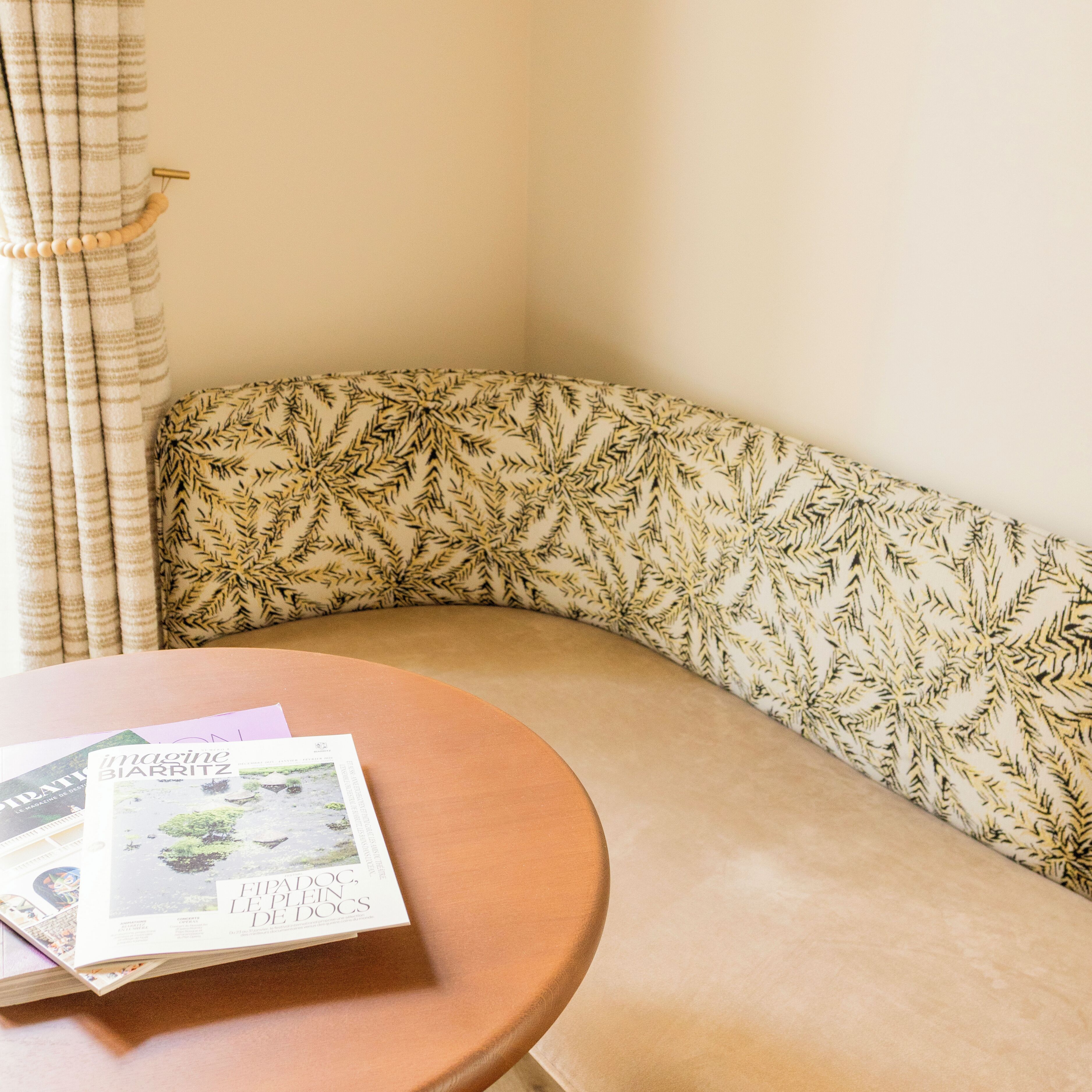 A corner with a patterned bench and a round table with magazines.