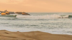 A beach with waves, a surfer, and rocky formations. - Hôtel St-Julien (Biarritz)