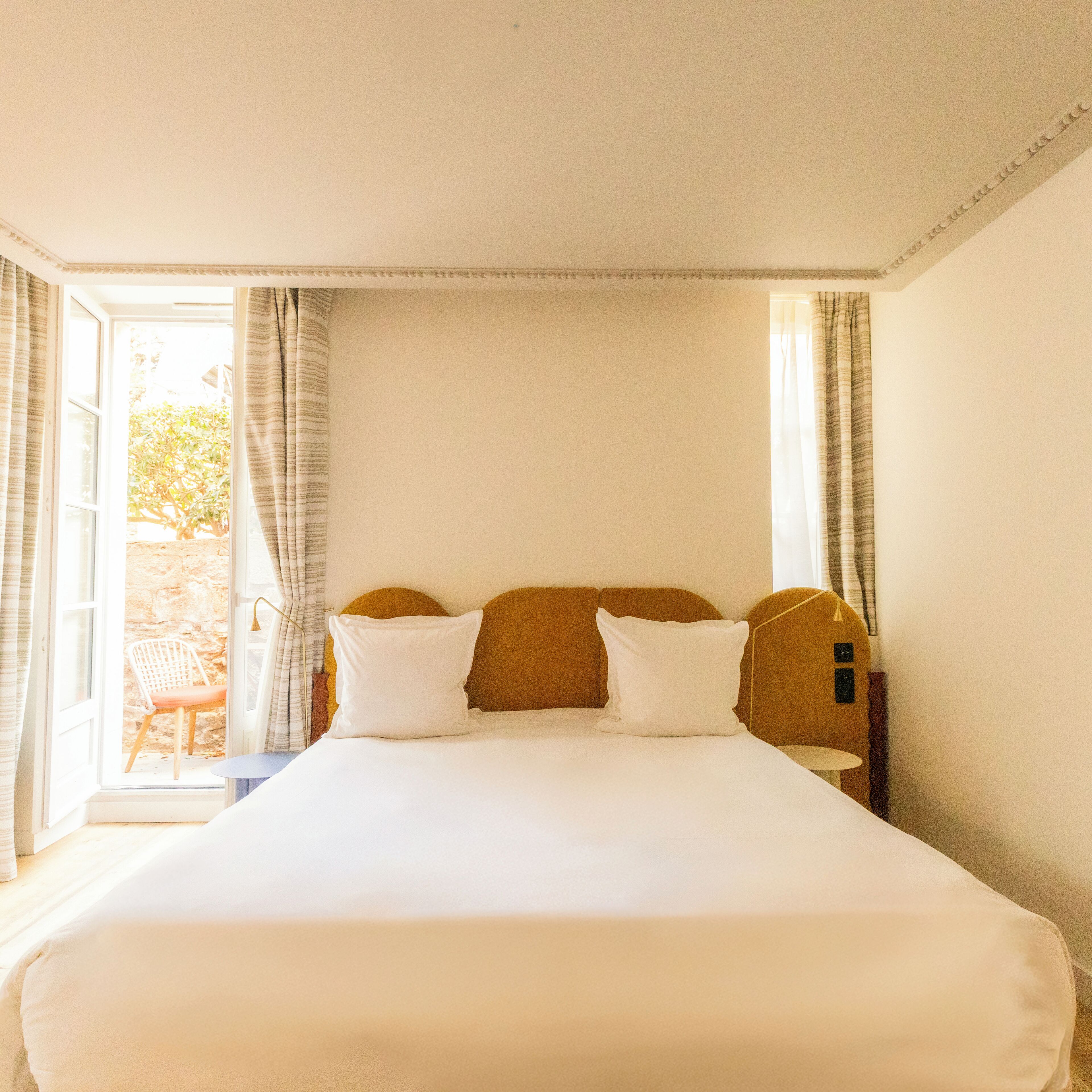 A bedroom with a large bed, a wooden headboard, and a view of the outdoors through an open door.