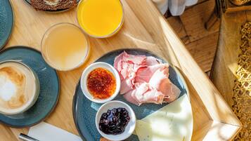 A breakfast tray with pancakes, orange juice, coffee, ham, cheese, and condiments.
