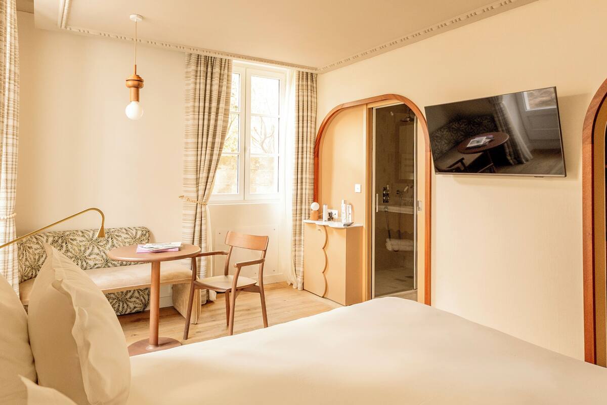 Ein Hotelzimmer mit einem Bett, einem Schreibtisch mit Stuhl, einem Fernseher und einer Dusche.