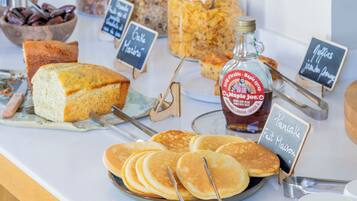 A breakfast buffet with pancakes, granola, and maple syrup.