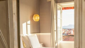 A bedroom with a bed, a window, and a view of buildings. - Hôtel St-Julien (Biarritz)