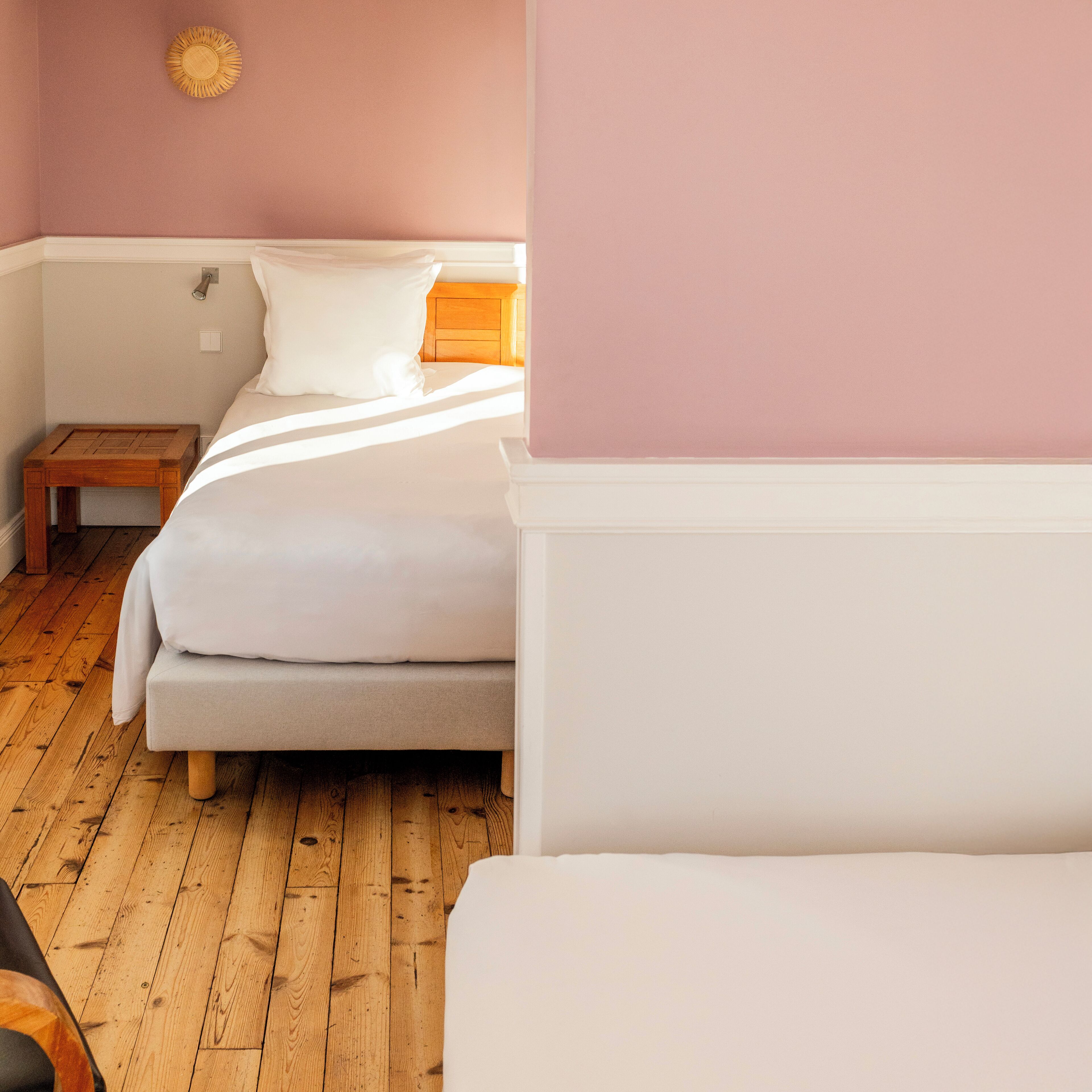 Un dormitorio con dos camas, suelo de madera, una mesita de noche y un reloj de pared.