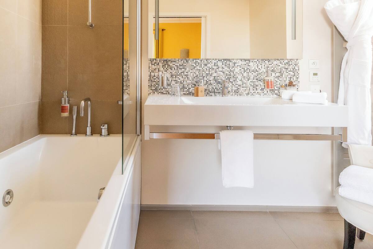 Ein modernes Badezimmer mit einer Duschkabine, einer weißen Badewanne und einem Waschtisch mit Spiegel und Waschbecken.