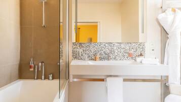 A modern bathroom with a glass-enclosed shower, a white bathtub, and a vanity with a mirror and sink.