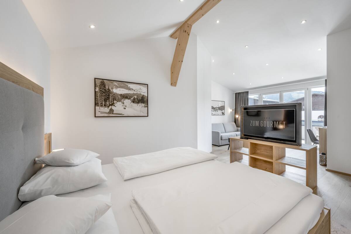 A modern bedroom with a large bed, a mounted TV, and a ski-themed painting.