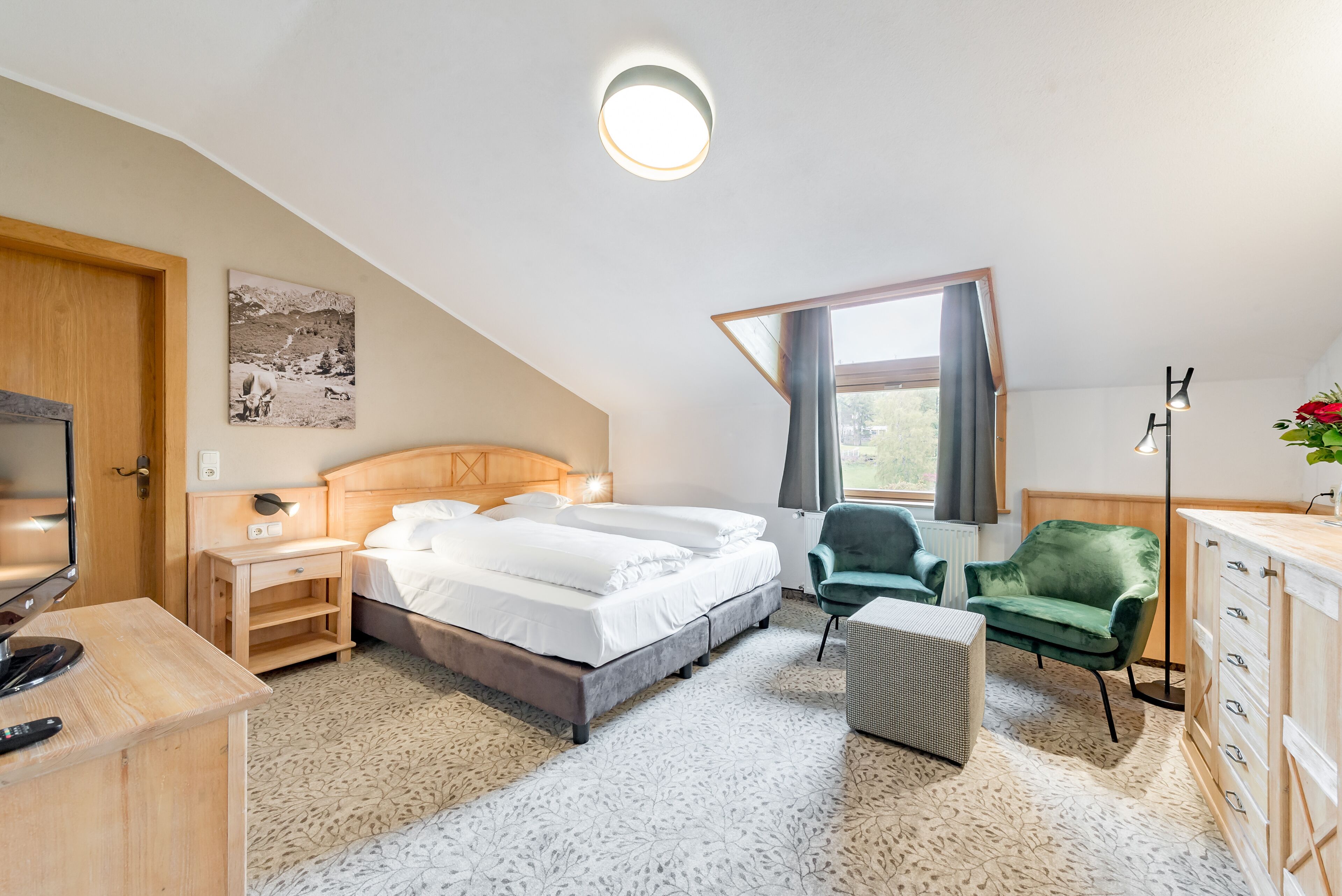 Un dormitorio con cama, escritorio, silla, televisor y ventana.