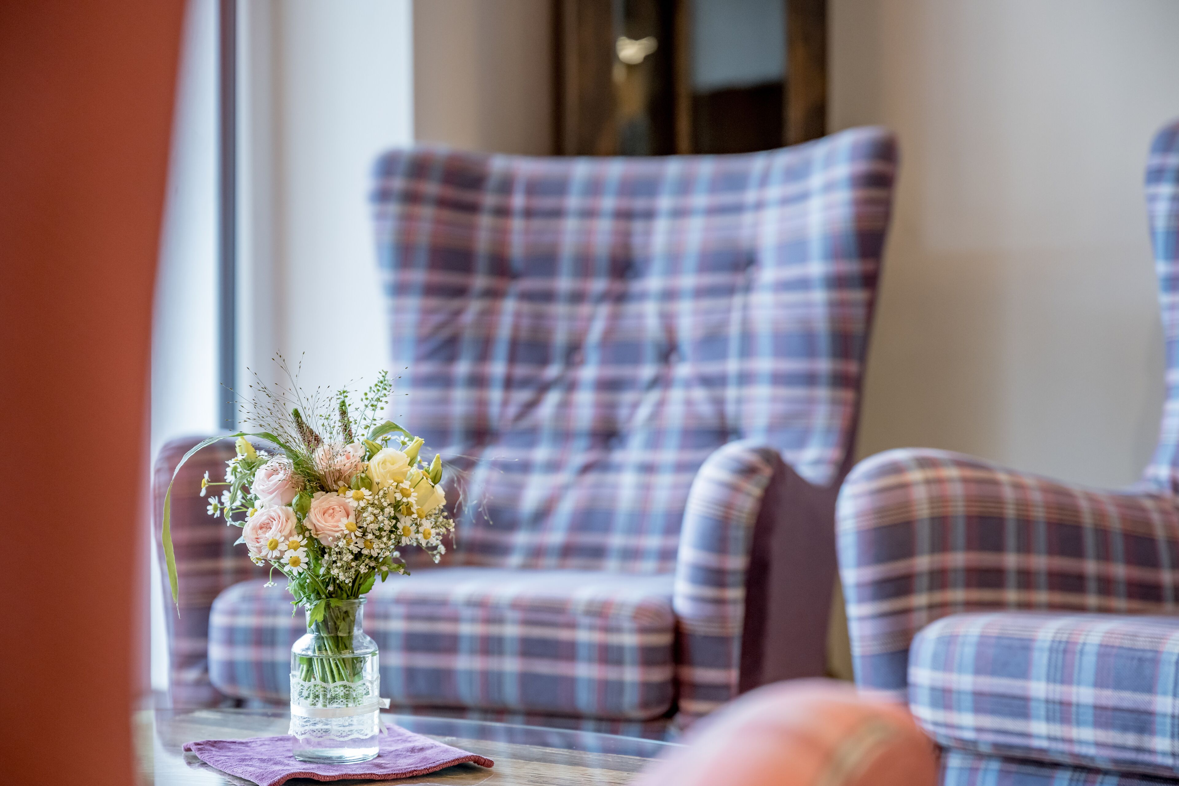 A plaid sofa in a room with a vase of flowers on a table.