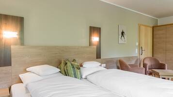 A hotel room with a large bed, two bedside tables, a wooden headboard, a wall-mounted light, a framed picture, and a wooden wardrobe.