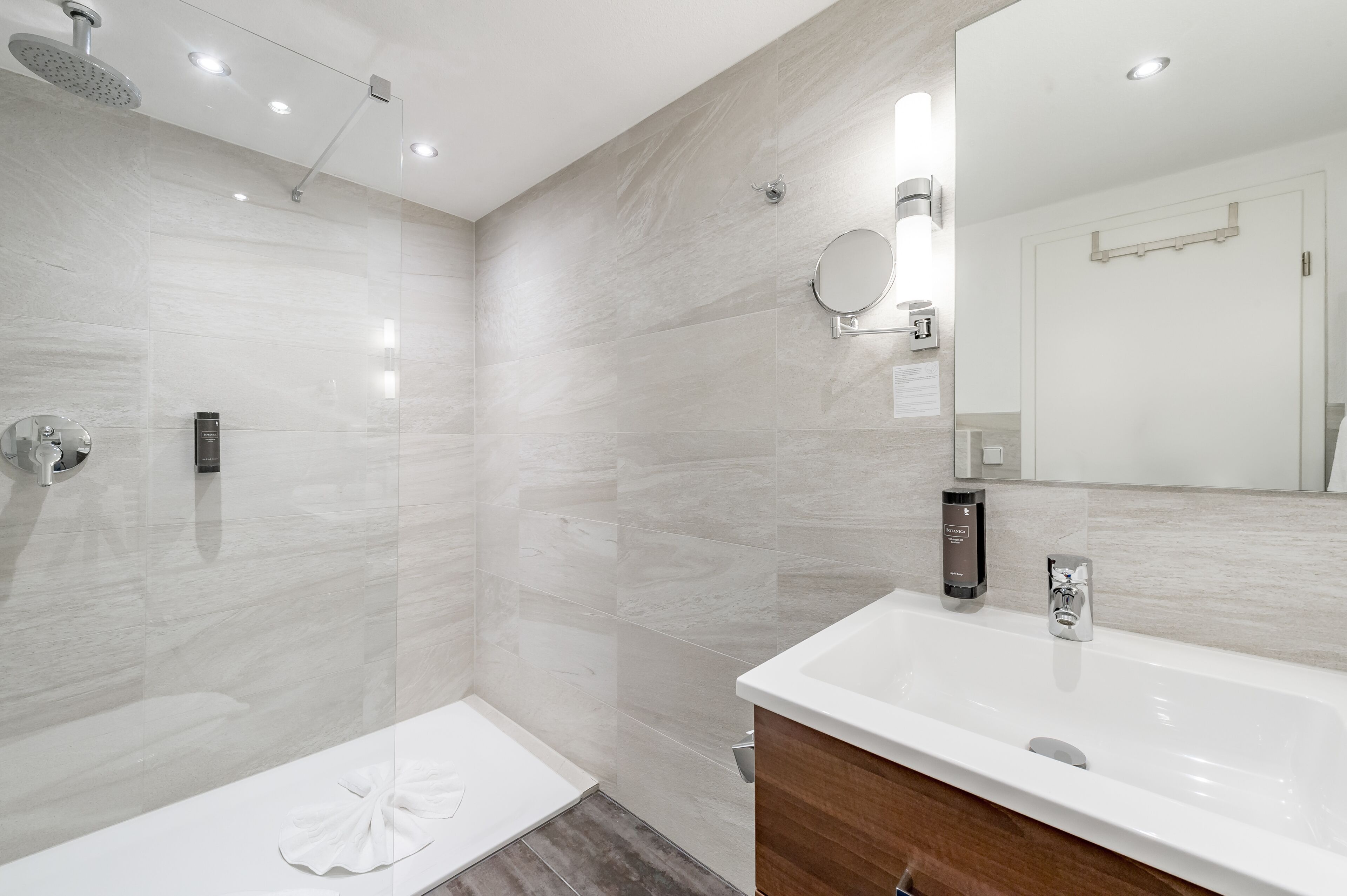 A modern bathroom with a shower, a sink, and a mirror.