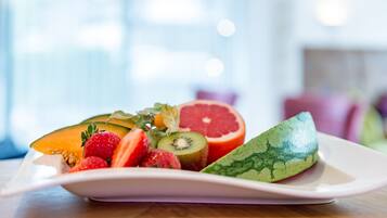 Un plato blanco con frutas cortadas, entre ellas sandía, kiwi, fresas y pomelo.
