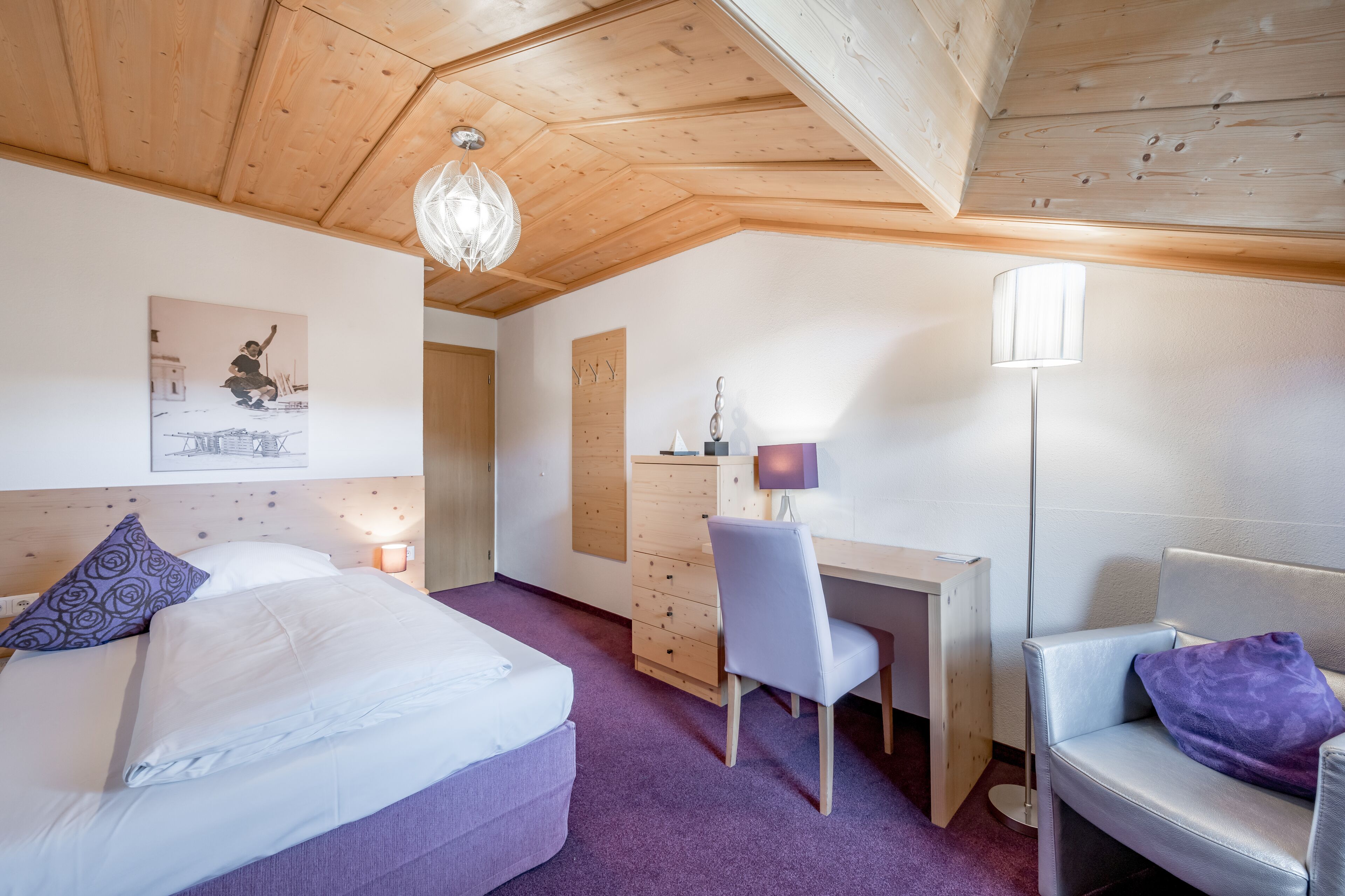Ein Schlafzimmer mit Bett, Schreibtisch, Stuhl und Lampe.