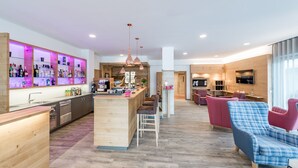 A modern kitchen with wooden cabinets, a central island, and bar seating. - Hotel zum Gourmet (Seefeld in Tirol)